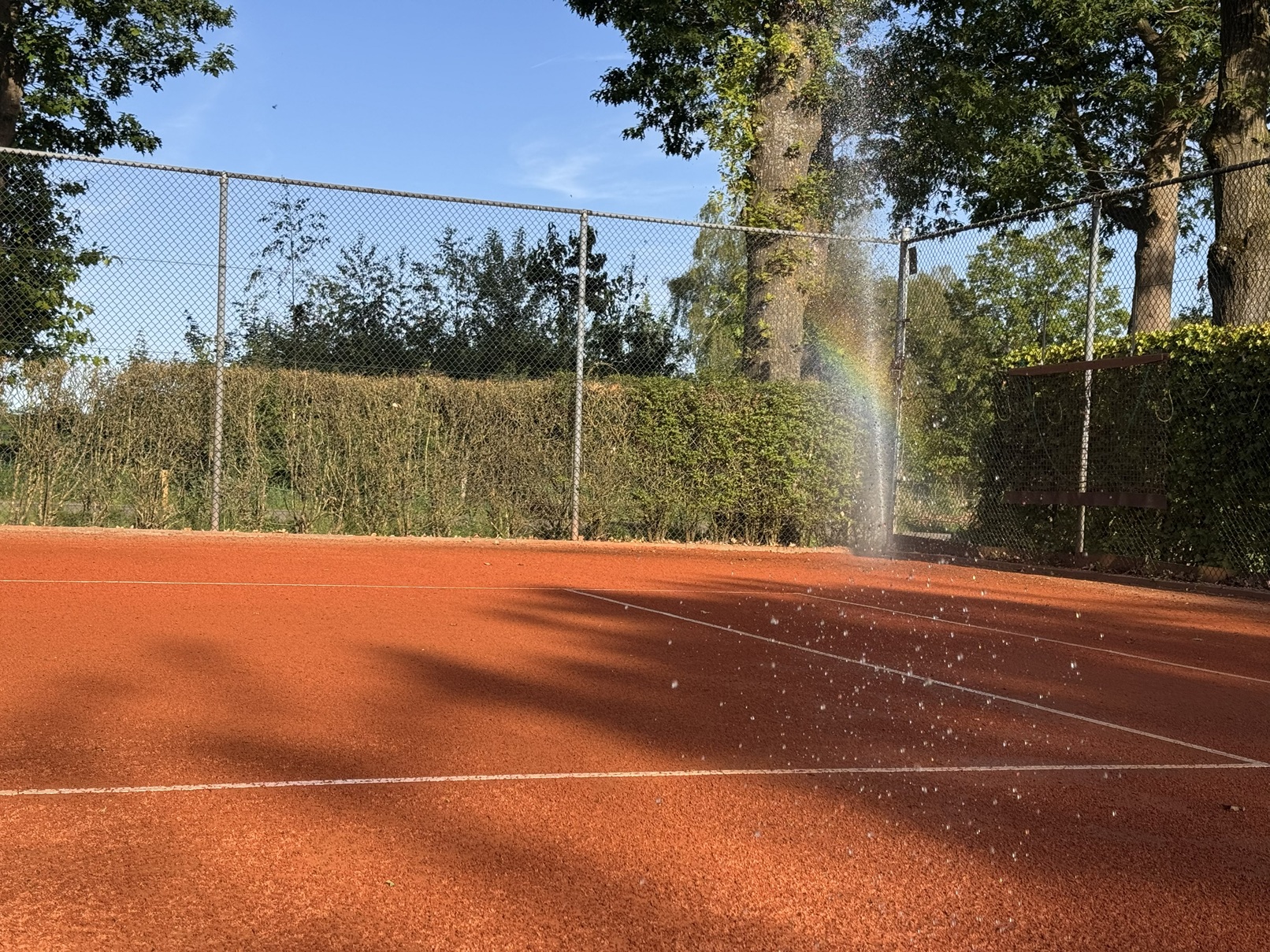 Sproeier in werking op de graveltennisbaan bij Raalte